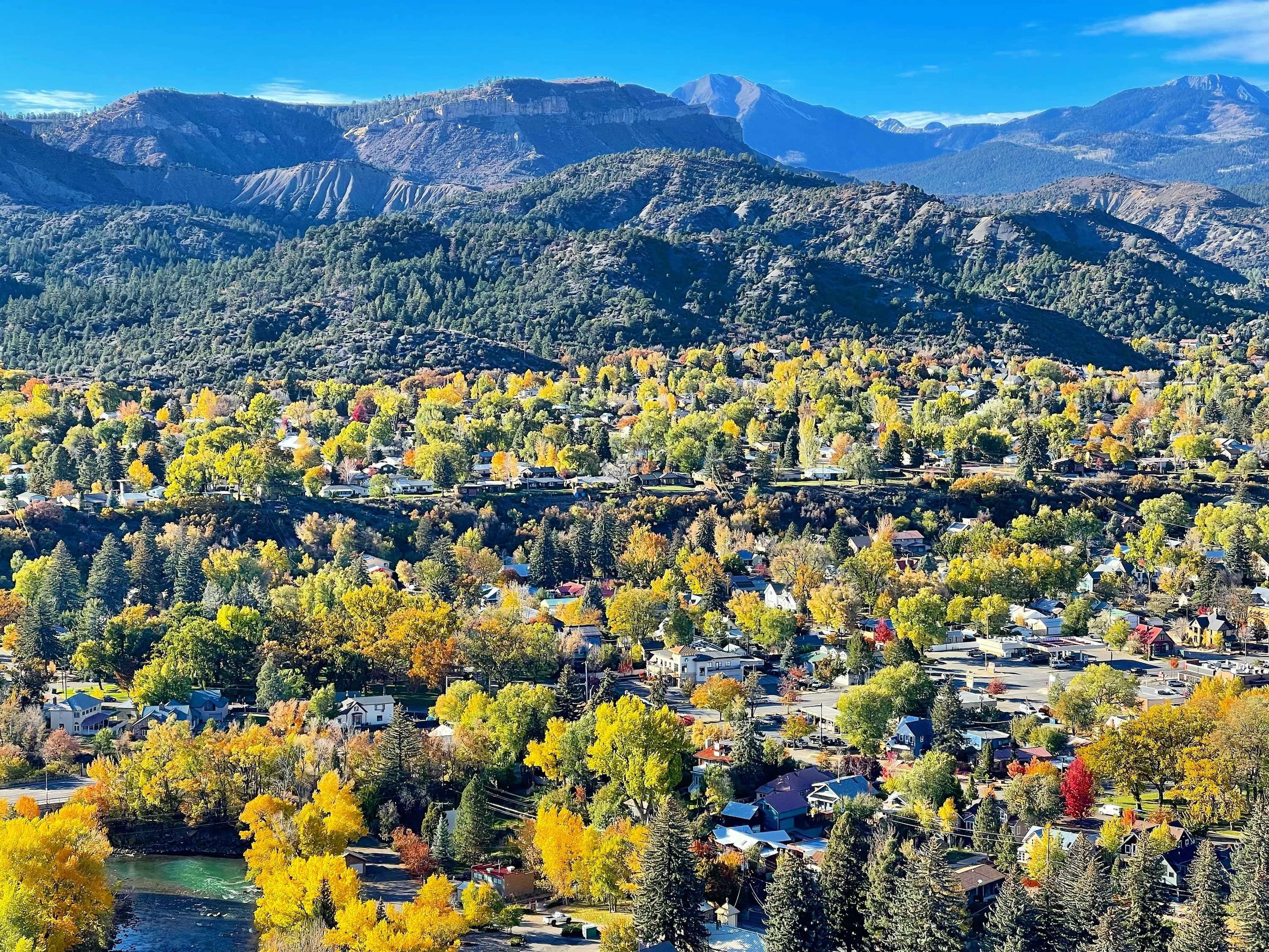 Durango in autumn from above: gold cottonwoods along the Animas River below forested hills and the San Juan Mountains